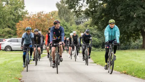 Ian Knight / Z70 Photography Cyclists riding out of Sandon Hall, flanked by grass and trees