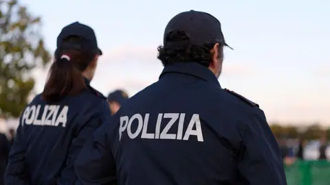 File photo: A woman and a man in Italian police uniform standing with their backs to the camera