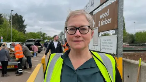 Vicky Beechey wearing a high-vis jacket in front of a recycling centre