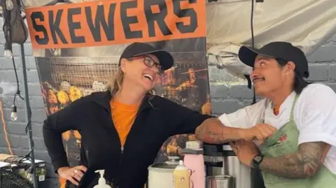 Submitted by Raegan Klein Raegan Klein and Alfredo Linares pose in front of their BBQ business