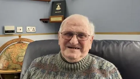 Phil Harrison/BBC Pembroke House resident retired Group Captain Keith Reyner smiling in the care home lounge