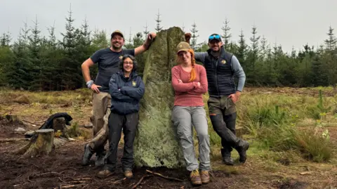 Tim Time Time Tim berdiri bersandar di Farley Moor Standing Stone