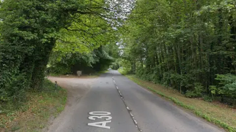 Google maps street view of the A30 in Salisbury. There is a junction to the left of the road. There are trees lining each side of the road.