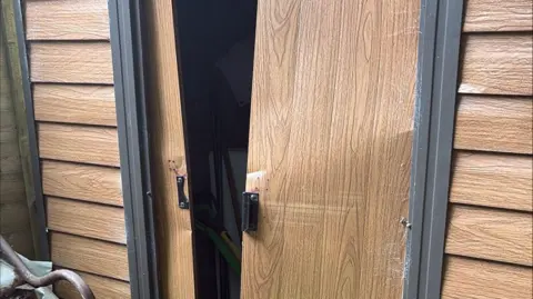 Jade Hoskin Shed doors that have been broken into. It is wooden with black handles. The doors have been forced open.