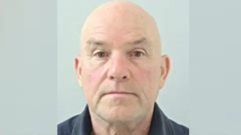 Lancashire Police A mugshot of Robert Crompton, a bald man wearing a black shirt.