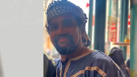 Muslim Imam in traditional dress looks at the camera