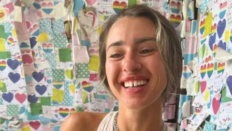 Gloucestershire Police Shelby Smith smiling in front of a background of heart notes stuck on a wall