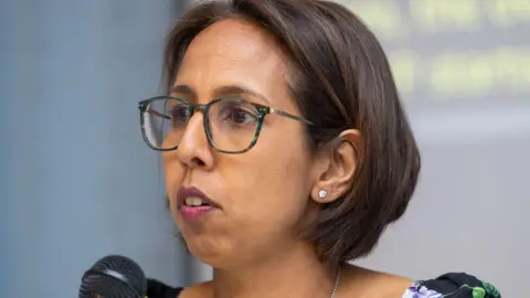 Getty Images Munira Wilson pictured from the shoulders up speaking at an event with the top of a microphone visible