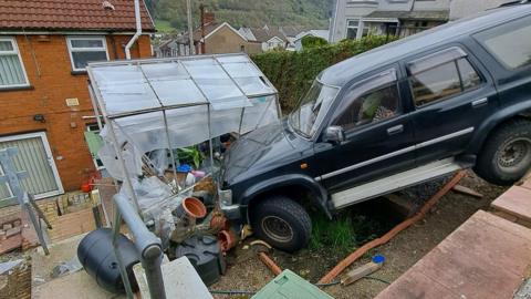 Car crashed into greenhouse and left dangling