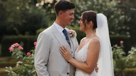 supplied A bride and groom embrace in a beautiful flower garden.