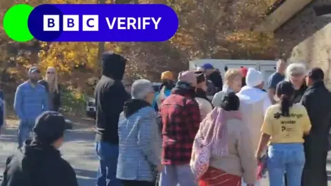 X Group of people outside a temporary election site in Pennsylvania, with trees in the background