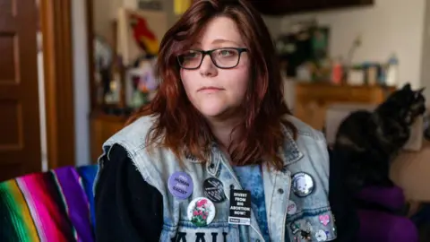 Getty Images Lauren Handy, pictured in 2022 wearing glasses and a sleeveless denim jacket covered in anti-abortion campaign badges