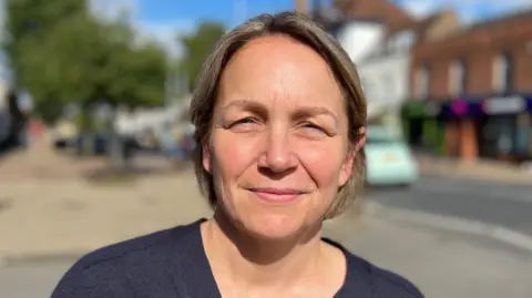 Simon Dedman/BBC Kerry is wearing a dark T-shirt on a quiet high street scene. She has short blonde hair.