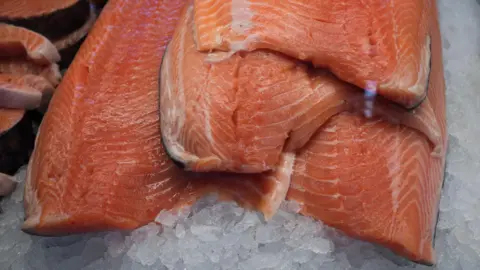 Salmon fillets stacked on ice.