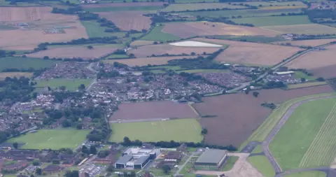 An aerial view of a village surrounded by fields and trees