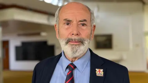 BBC A man with a beard in a blue shirt and jacket 