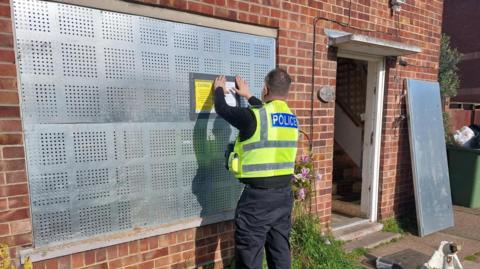 Police officer putting up a closure notice