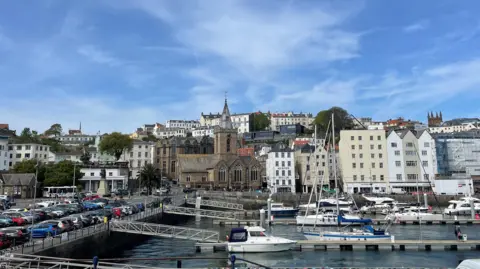 A view of St Peter Port, showing the harbour, buildings and cars.