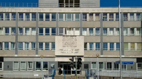 The outside of of Croydon Magistrates Court, a cream and gray building lined with windows, in South London