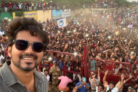 x Vijay taking a selfie at one of his rallies