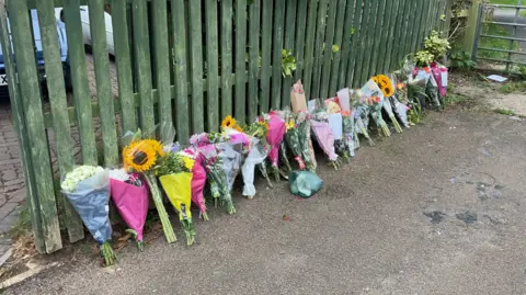 Flowers left by a fence