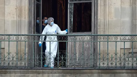 A French Forensics Officer examines the cut window and balcony of a gallery at the Louvre Museum which was the scene of a robbery at the world famous museum earlier in the day on October 19, 2025 in Paris