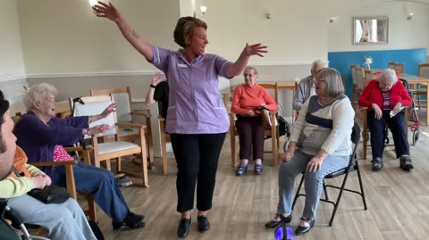 Rachael Addy stood in a circle of residents with her hands in the air, wearing her tap shoes.