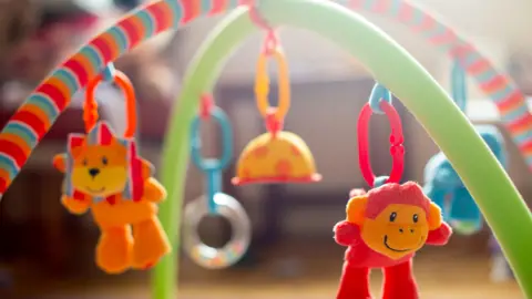 The PA media is a baby mobile on an activity mat, with a soft toy lion and monkey hanging from its frame.