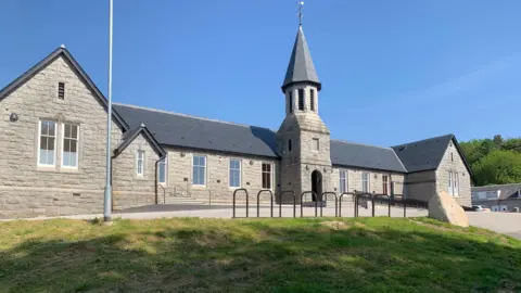 An single-storey granite building with a tower over the main entrance