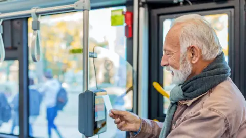 Getty Man with a beard swipes card on bus