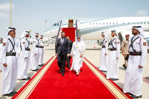 Reuters O presidente sírio, Ahmed al-Sharai, caminhando no tapete vermelho após um avião em Doha antes da cúpula de emergência de líderes árabes-islâmicos
