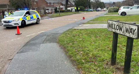 Adrian Harms/BBC A sign into Willow Way, Guildford, which is affected by the closure of Hazel Avenue. A police car and officer can be seen ahead of a cordon.