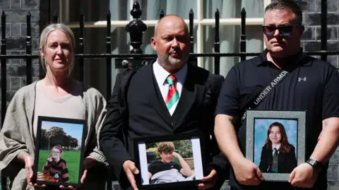 EPA Stuart Stephens is joined by two other parents outside Downing Street holding up images of their deceased children.