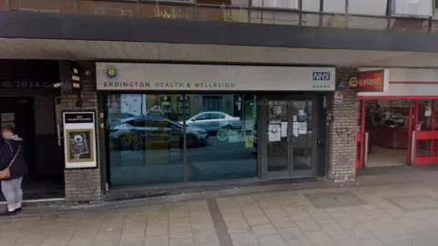 Google The front entrance to a high street unit with the words Erdington health and wellbeing above the doors