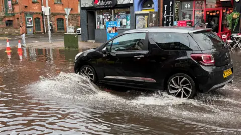 A black car driving through flood waters