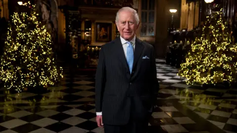 PA Media King Charles in front of Christmas trees in Westminster Abbey which were used for the Princess of Wales's carol concert