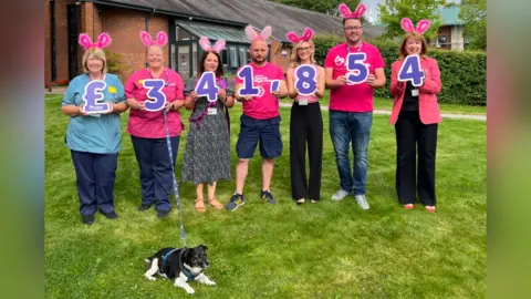 Supplied People hold up figures detailing the total raised