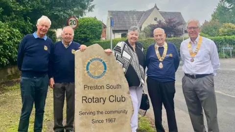 Members of the rotary club stand around the newly installed stone marker on Liverpool Road which reads Preston South Rotary Club - Serving the community since 1967.