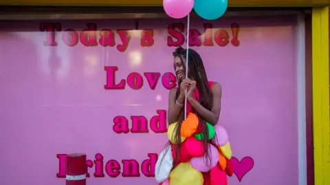 Southampton Forward A woman stood in front of a pink poster wearing a colourful outfit.