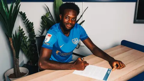 Abu Kamara poses for a photo after signing for Portsmouth 