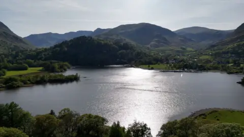 A lake surrounded by green hills and trees
