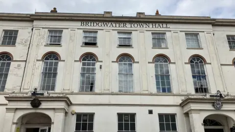 BBC The exterior of cream stone coloured building with 'Bridgwater Town Hall' written in black lettering at the top and big glass windows.