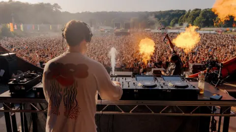 Elliot Hingston A DJ plays to a huge crowd at the Love Saves the Day Festival in Bristol. Flame throwers decorate the stage. 