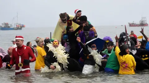 Getty Images Dozens of people dressed up as superheroes in the sea in Tenby.