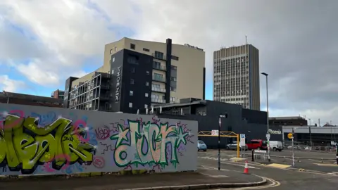 Grey graffiti-covered fencing in front of Leicester's Phoenix Cinema