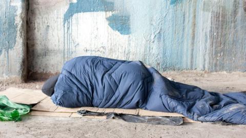 Image of somebody sleeping rough in a sleeping bag on the street