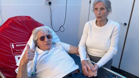 Brian Jones in a hospital bed in the Emergency Department with his wife