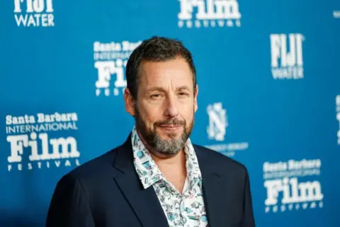 Adam Sandler at a film festival wearing a patterned blue shirt