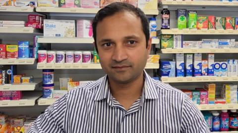 a man in front of pharmacy shelves