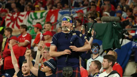PA A Scotland fan plays the bagpipes
